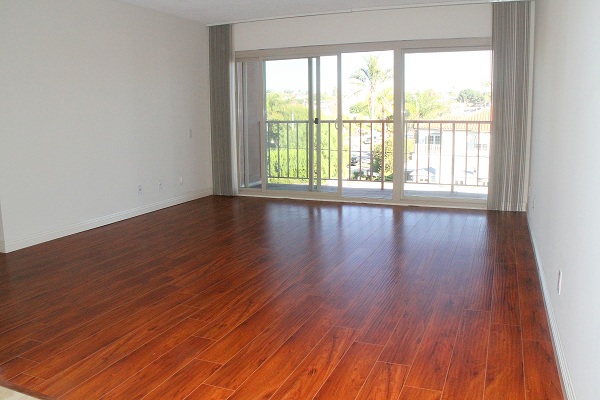 Very large living room with hardwood floor opening to large balcony